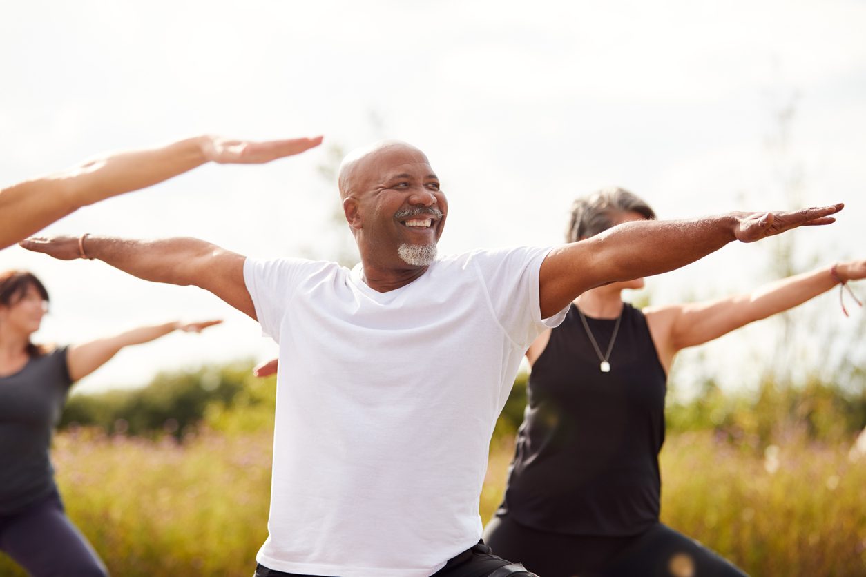 Group Of Mature Men And Women In Class At Outdoor Yoga Retreat Employee on Computer