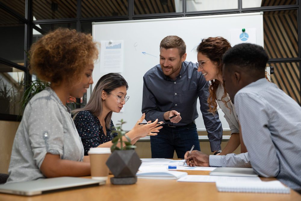 Group of confident business partners working with laptop in office