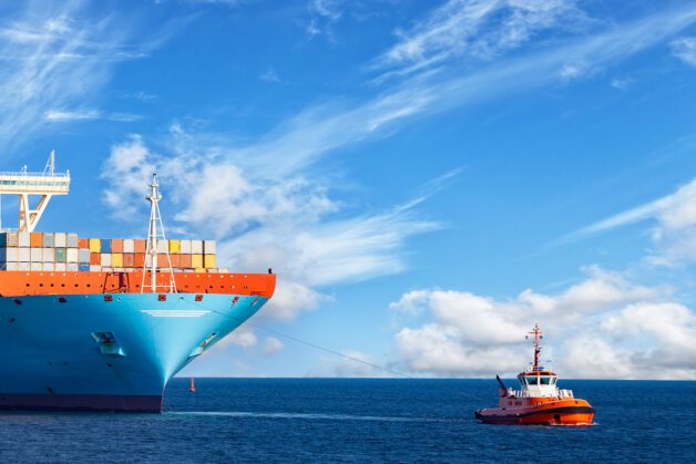 Tugboat,Towing,A,Large,Container,Ship,On,Sea.